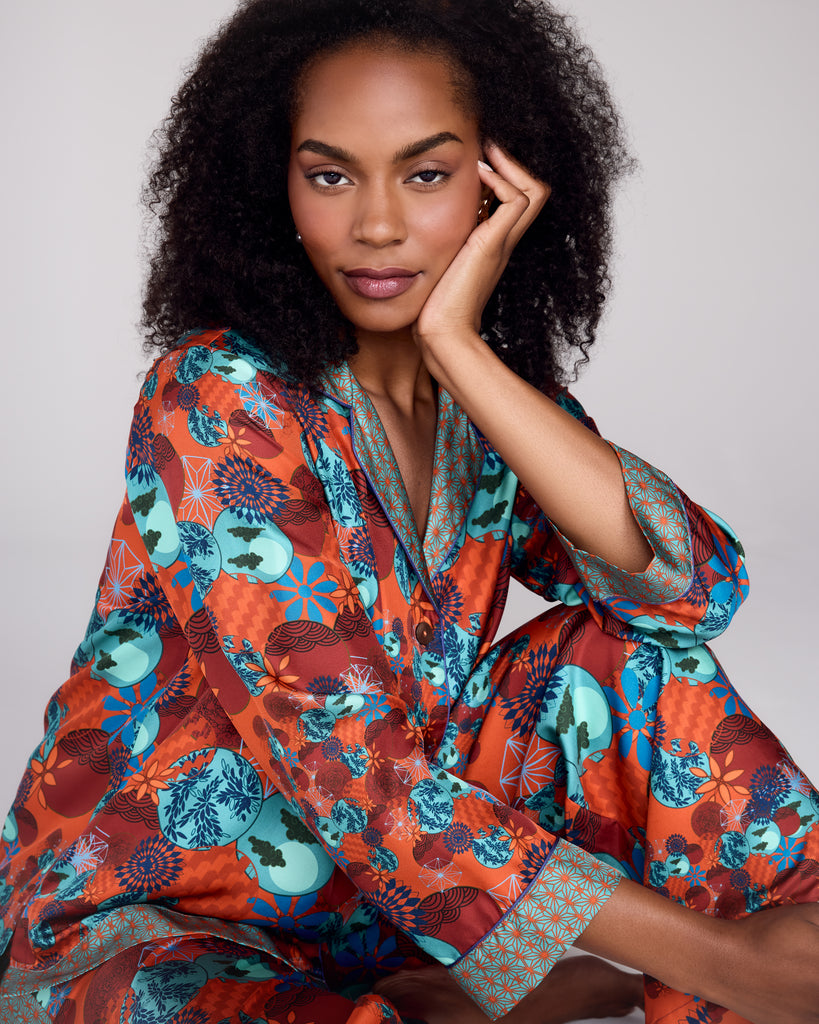 Exquisite Tama Coral silk pajama from Karma on the Rocks is crafted from a luxurious coral red silk twill with a a Japanese-inspired print showcasing clouds, suns, foliage and geometric designs in shades of red, teal and blue