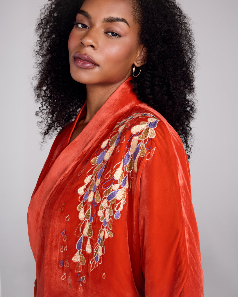 Quilted Hanten bed jacket from Karma on the Rocks is crafted from a vibrant red silk velvet with a teardrop embroidery in shades of gold, silver and purple draping over one shoulder and at the cuffs 