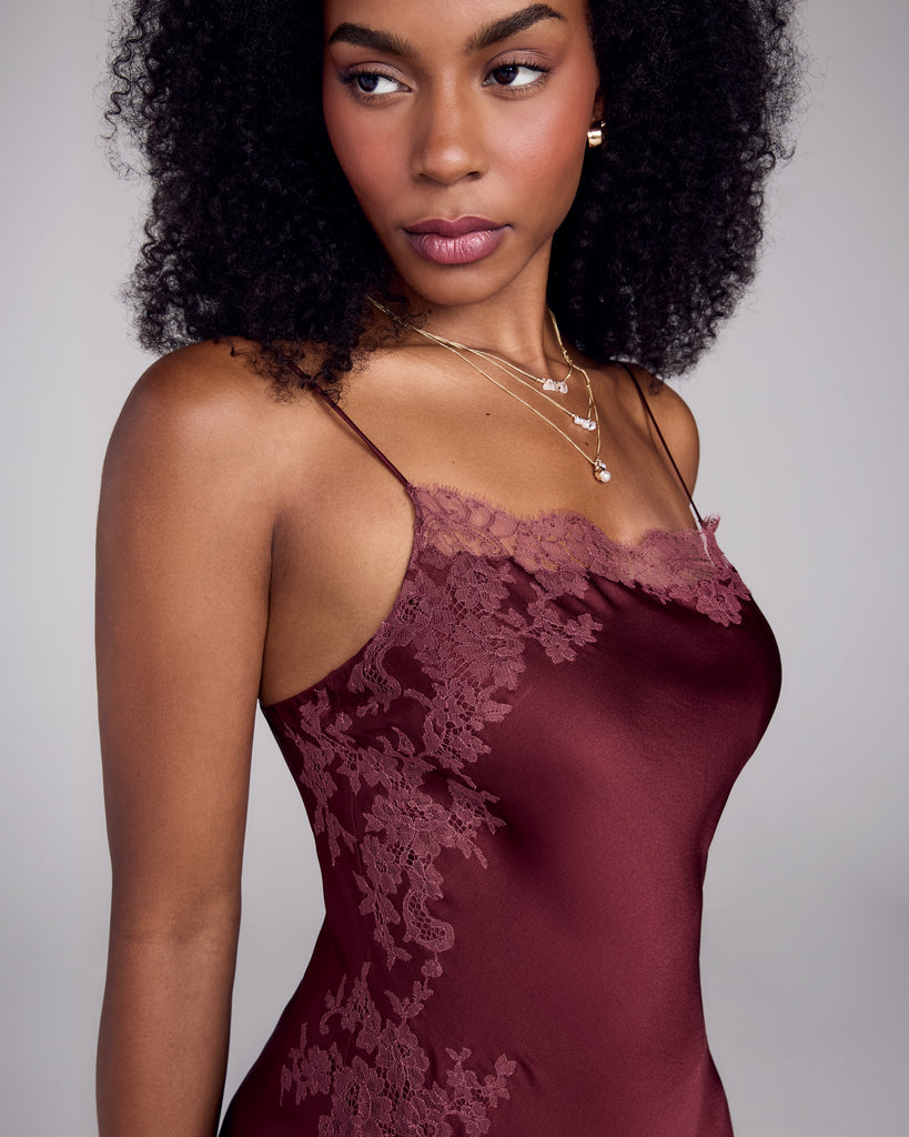Sheer red lace ornaments the straight neckline, while intricate appliqué decorates one entire side of the garment in Merle Noir's carmine silk slip dress