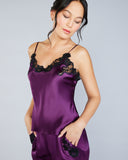 The Clara silk pajama set from Emma Harris is crafted from a rich purple silk with shimmering black floral lace appliqué