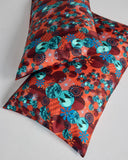 Tama Coral Silk pillowcases from Karma on the Rocks are crafted from a luxurious coral red silk twill with a a Japanese-inspired print showcasing clouds, suns, foliage and geometric designs in shades of red, teal and blue
