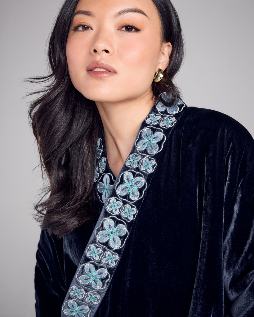 Quilted Hanten bed jacket from Karma on the Rocks is crafted from a navy blue silk velvet with a geometric floral embroidery in shades of silver, blue, teal and white at the shawl collar and at the cuffs