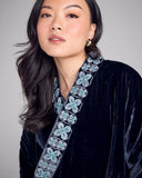 Quilted Hanten bed jacket from Karma on the Rocks is crafted from a navy blue silk velvet with a geometric floral embroidery in shades of silver, blue, teal and white at the shawl collar and at the cuffs