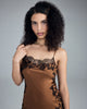 Merle Noir's blazing bronze slip dress has thin adjustable spaghetti straps and sheer black lace at the neckline and hem
