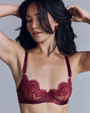 Underwired Seraphina Ruby bra from Seelanii has sheer red cups with lace appliqué and gold beading, adjustable custom-dyed red shoulder and back straps, and a gold-toned back closure