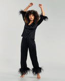 Black stretch silk Esme lounge set from Gilda & Pearl is elevated by sustainably-sourced feather accenting at the cuffs on sleeve and trouser hem