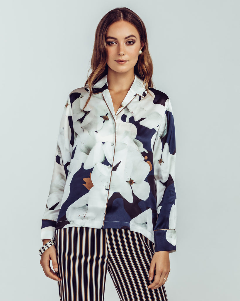 Camo Bloom silk blouse is patterned with an oversized magnolia print in shades of black, navy, white, and brown